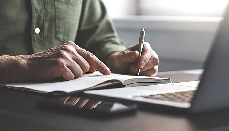 استخدم المفردات اليومية شخص يجلس أمام اللاب توب وفي يديه قلم 