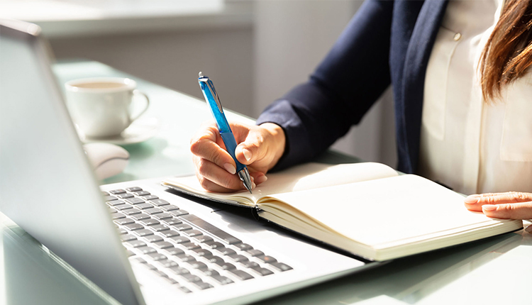 استراتيجيات كتابة المحتوى وكاتبة تكتب في النوت الخاص بها وامامها لابتوب